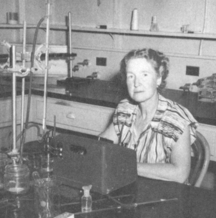 Black and white photo of scientist seated in lab.
