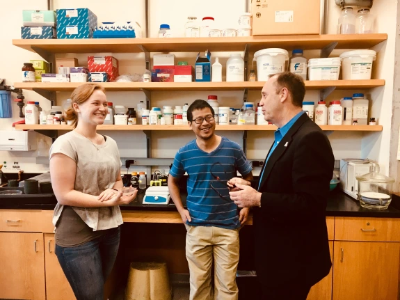 Two students from a School of Plant Sciences laboratory speaking with the Vice President Burgess.